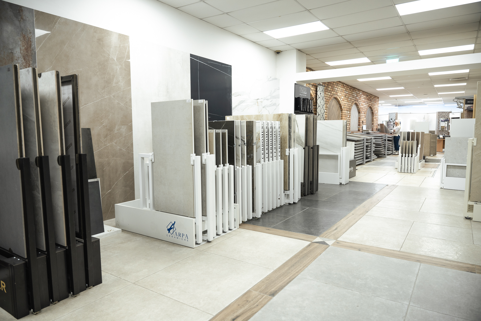 Large format tiles on display racks in the showroom, with wood-effect strips laid between the floor tiles